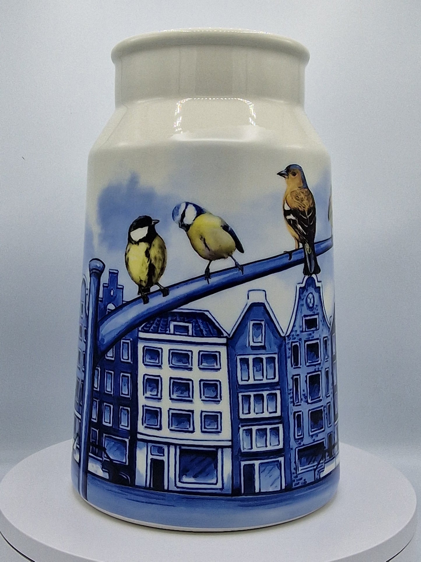 Unieke vaas in melkbusstijl met blauwe grachtenpandillustraties, een iconisch Nederlands souvenir.