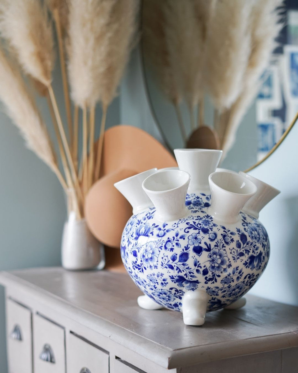 Detail van keramieken tulpenvaas op pootjes met bloemmotief en traditionele Delfts blauwe decoratie