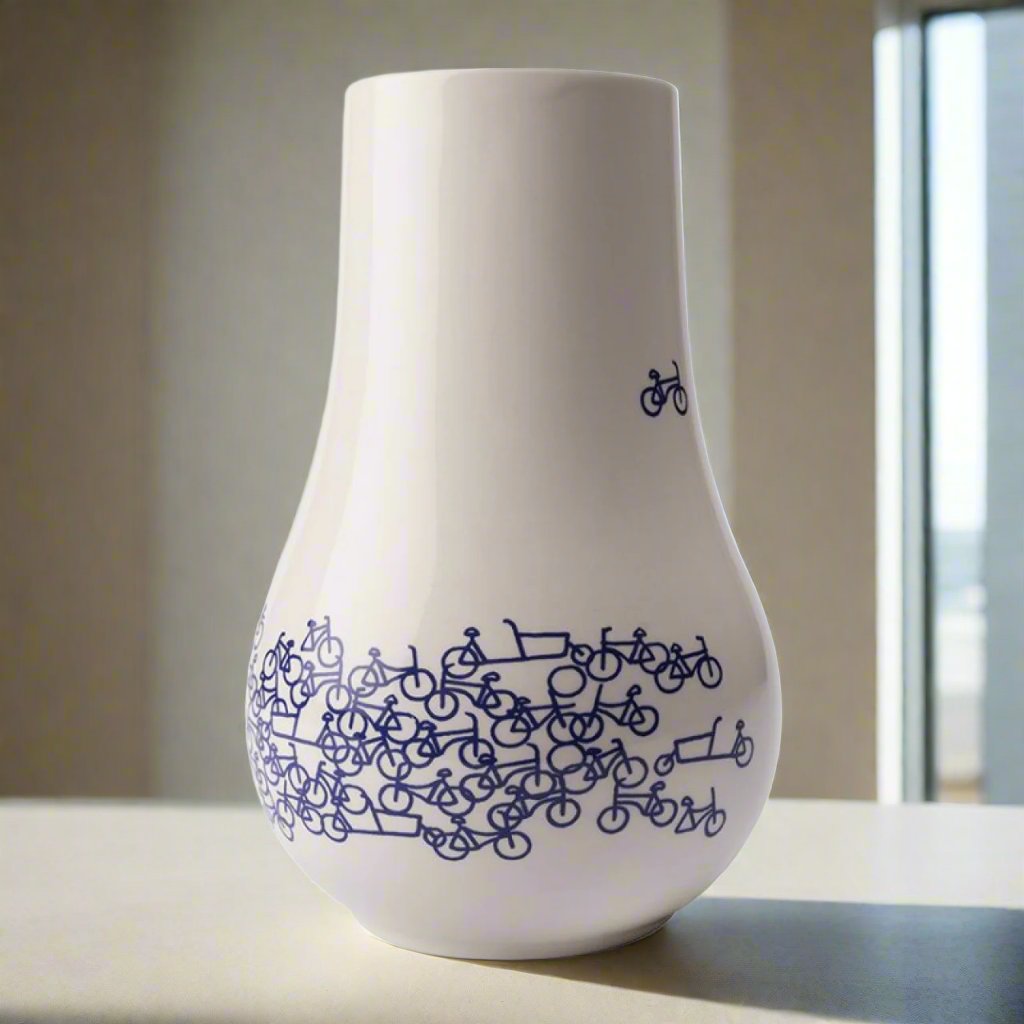 De Blauwe Fietsvaas Nr. 1 - een moderne keramische vaas in Delfts blauwe stijl, ontworpen door Sylvain Tegroeg. De vaas heeft een diameter van 13 cm en een hoogte van 21 cm, en is bedrukt met een fietsontwerp, symbool voor Nederlands erfgoed